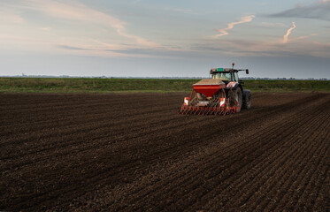 Obraz premium Farmer with tractor seeding - sowing crops at agricultural field