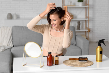 Beautiful young happy woman using care products and brushing her short hair at home