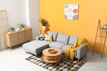 Interior of beautiful living room with cozy sofa, houseplants, cushions and coffee table