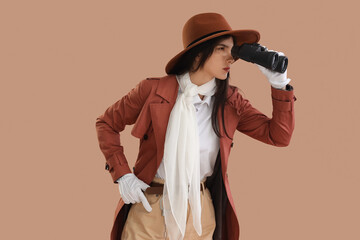 Female spy looking through binoculars on beige background