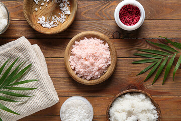 Composition with natural body scrubs, ingredients and palm leaves on wooden background