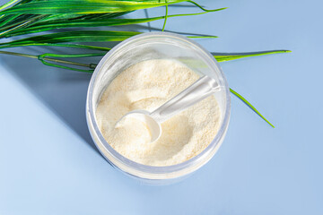 Powder in jar with measuring spoon on blue background. Protein, collagen 
