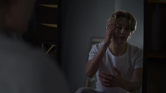 Pensive woman looks at lace reflection sitting by mirror