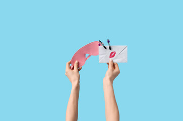 Woman holding sex toys with letter on blue background. Valentine's Day celebration