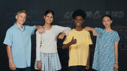 Group of smart multicultural teenager looking at camera at blackboard. Happy diverse children...