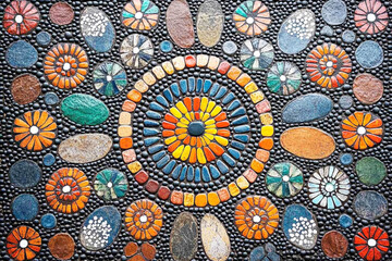 Fototapeta premium Colorful mosaic artwork with circular floral patterns and textured stones in vibrant tones of orange, blue, and green