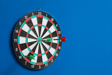 Dartboard with darts hanging on blue wall