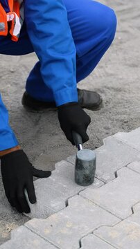 Worker laying interlocking paving stones on a construction site