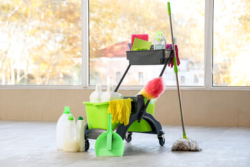 Fototapeta premium Trolley with cleaning supplies near window in room