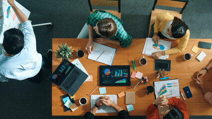 Top view of smart business man standing while writing and presenting marketing idea at whiteboard. Group of diverse happy people looking at stock market chart and listening presentation. Convocation.