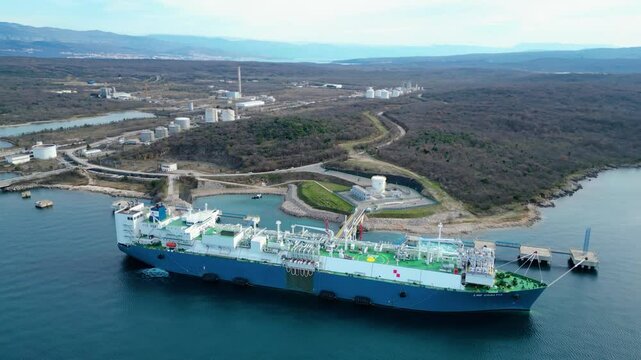 Spectacular aerial drone shot of the LNG (liquefied natural gas) terminal on Krk Island, Croatia, featuring a massive gas tanker docked at the facility