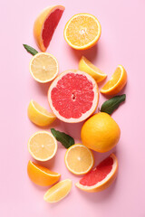 Different cut citrus fruits with leaves on pink background