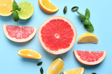 Different cut citrus fruits and mint leaves on blue background