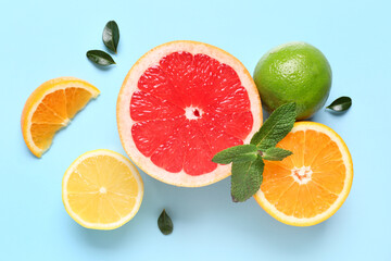 Different cut citrus fruits and mint leaves on blue background