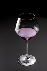 Goblet glass of red wine on black background