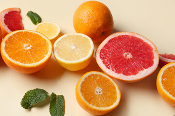Different cut citrus fruits and mint leaves on beige background