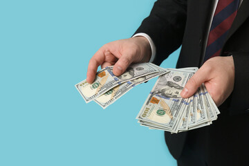 Businessman counting dollar banknotes on blue background, closeup
