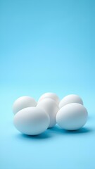  White eggs isolated on light blue background with space for text, lying horizontally. Minimalist design.