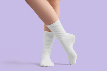 Legs of young woman in stylish white socks on lilac background