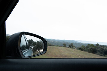 rear-view mirror and car part in nature landscape giving a holiday and road trip atmosphere