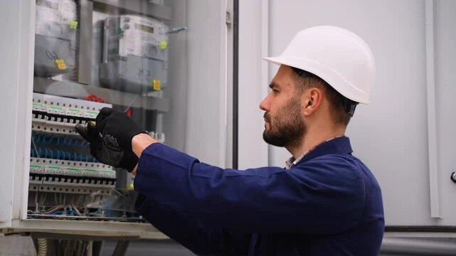 Electrician repairing electrical panel with screwdriver