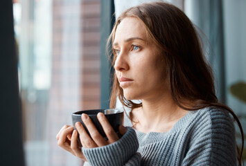 Depression, woman and thinking at window with coffee, anxiety and bad memories in home. Victim, tea...