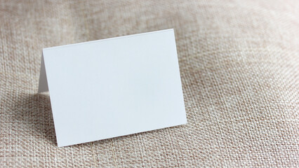Folded blank white card resting on burlap background, an empty space for your text