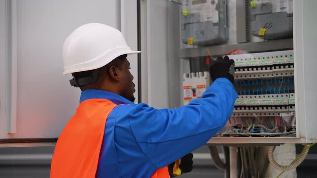 African American electrician repairing an outdoor electrical panel