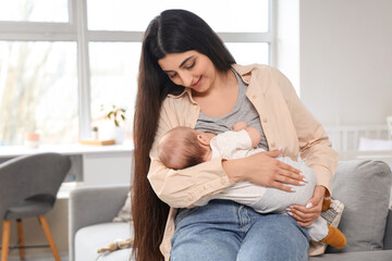 Young woman breastfeeding her baby in children's room at home