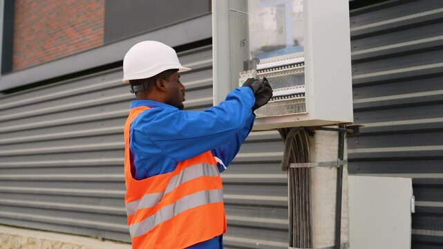Electrician installing an outdoor electrical panel near duplex