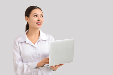 Young Asian businesswoman using modern laptop on white background