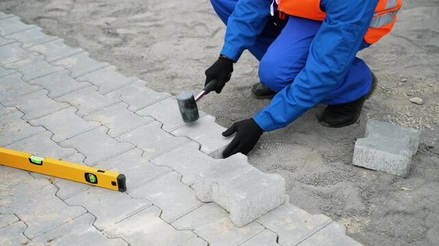 Worker laying interlocking paving stones on a construction site