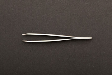 Top view extreme macro photography of white metal tweezers isolated on black background