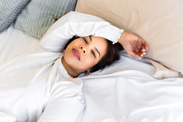 Obraz premium Latin woman resting in bed enjoying sleep hygiene routine