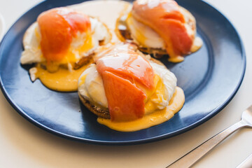Eggs Benedict with salmon and hollandaise sauce on a blue plate. Concept: a delicious and healthy breakfast.