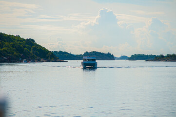yacht traversing serene waterway with lush green hills.