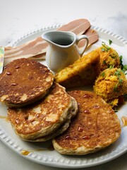 American Breakfast with pancakes, syrup, eggs, hash brown and bacon