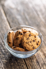 Chocolate chip cookies in bowl on wooden table.