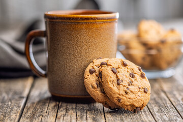 Chocolate chip cookies and mug on wooden table.