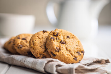 Chocolate chip cookies on napkin on white table.