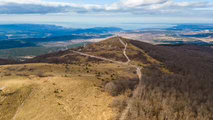 A breathtaking aerial drone view of Slavnik, one of Slovenia's most iconic peaks, standing at 1,028 meters above sea level. Located in the Karst region near the border with Croatia