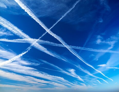 a blue sky filled with clouds and contrails