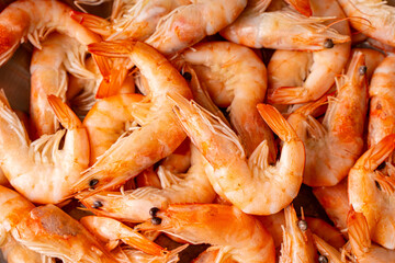 Frozen, boiled shrimp. Texture King prawns background. Seafood on the counter. Fish market. Close-up shot of seafood. Photo of shrimp in a supermarket. Wholesale of seafood.