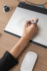A sophisticated woman in the office, elegantly using a stylus on a drawing tablet, immersed in her...