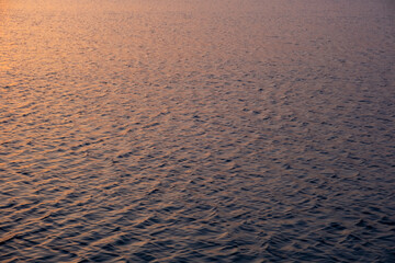Waves in the sea with yellow to pink reflections from sunset