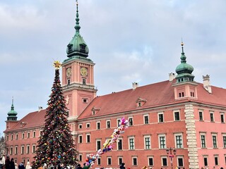view of the big christmas tree in front of the castle in the old town of warsaw with its tower and clock on a cold december day
