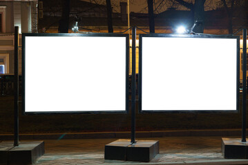 Double square billboard at night in a city square.
