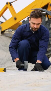Construction worker leveling pavement near heavy machinery