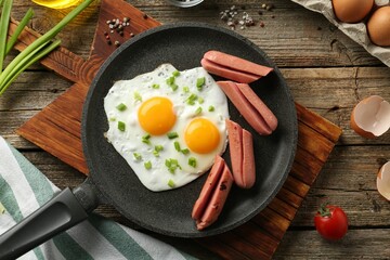 Tasty fried eggs with cut sausages served on wooden table, flat lay