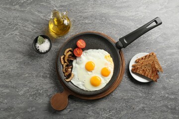 Tasty fried eggs with mushrooms served on grey table, flat lay